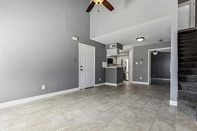 unfurnished living room featuring ceiling fan, a towering ceiling, and light tile patterned floors