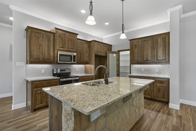 kitchen with appliances with stainless steel finishes, dark hardwood / wood-style flooring, sink, and a center island with sink