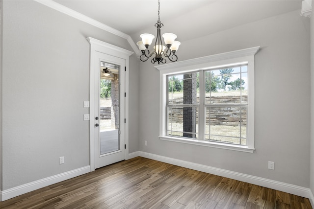 doorway with ornamental molding, a notable chandelier, and wood-type flooring