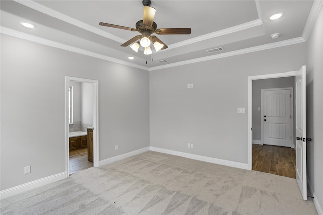 carpeted empty room featuring a tray ceiling, ornamental molding, and ceiling fan