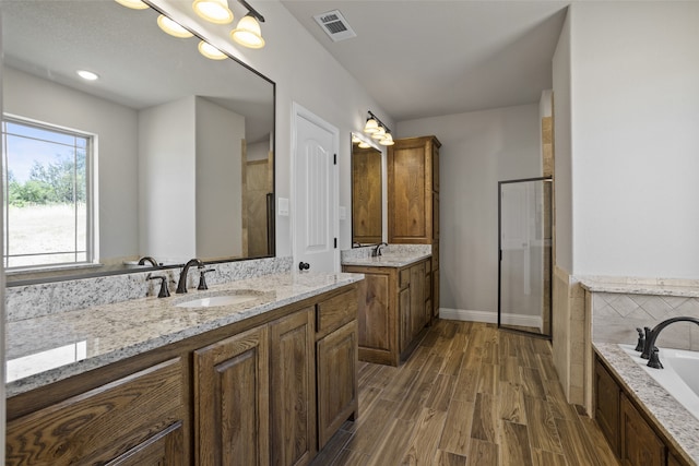 bathroom featuring vanity, hardwood / wood-style flooring, and plus walk in shower