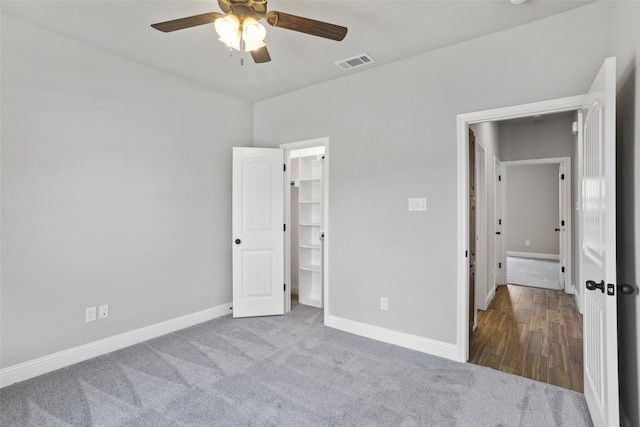 unfurnished bedroom featuring hardwood / wood-style floors, a walk in closet, ceiling fan, and a closet