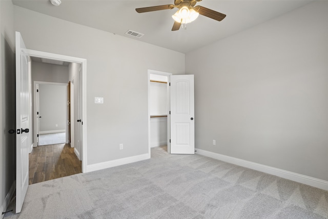 unfurnished bedroom with wood-type flooring, a spacious closet, and ceiling fan