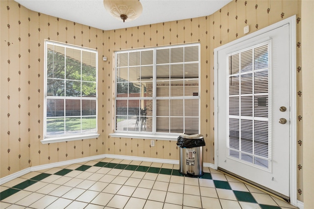 unfurnished room featuring wallpapered walls, baseboards, and a textured ceiling