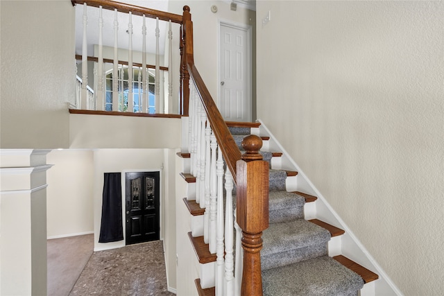 stairway with a textured wall and baseboards