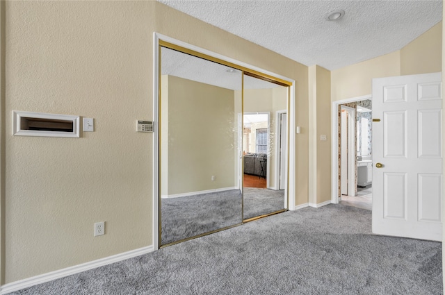 unfurnished bedroom with baseboards, a textured wall, a textured ceiling, carpet flooring, and a closet