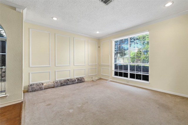 carpeted empty room featuring a textured ceiling, recessed lighting, a decorative wall, visible vents, and ornamental molding