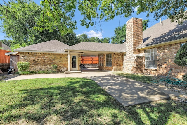 view of front of property with roof with shingles, a chimney, a front lawn, and brick siding