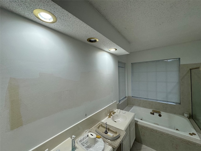 full bathroom featuring a textured ceiling, a tub with jets, and vanity