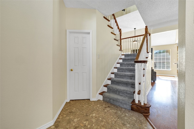 stairway with baseboards and a textured ceiling