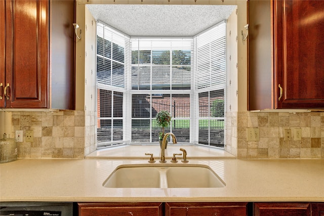 kitchen with reddish brown cabinets, dishwasher, light countertops, and a sink