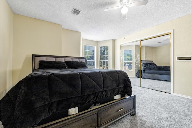 bedroom with a closet, light colored carpet, visible vents, a ceiling fan, and a textured ceiling