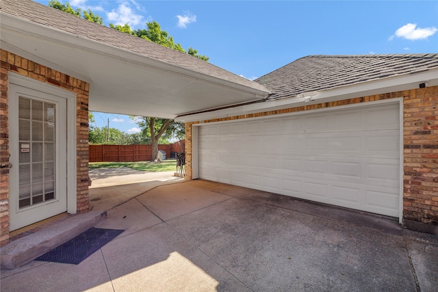 garage featuring driveway and fence