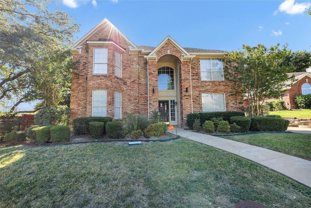 traditional-style home with brick siding and a front lawn