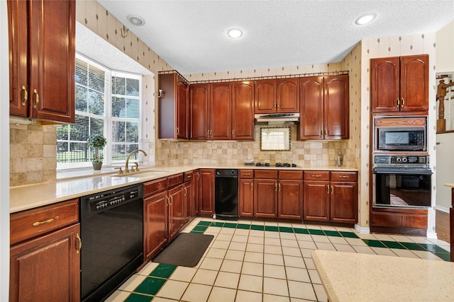 kitchen featuring under cabinet range hood, light countertops, a textured ceiling, black appliances, and a sink