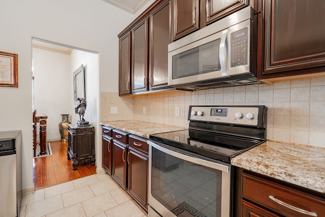 kitchen featuring light wood-type flooring, light stone counters, decorative backsplash, and stainless steel appliances