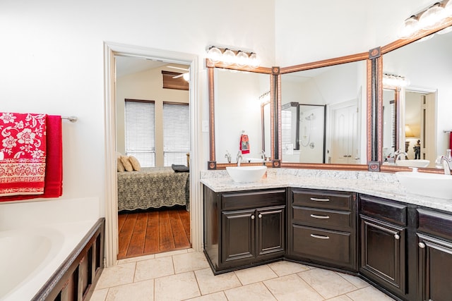 bathroom with a washtub, vaulted ceiling, double sink vanity, and tile patterned flooring