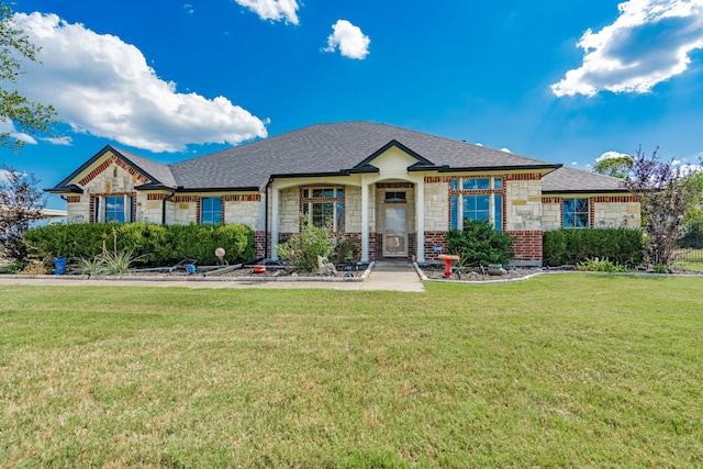 view of front of home with a front yard, stone siding, and roof with shingles