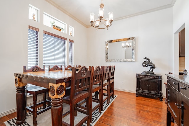 dining space with a notable chandelier, crown molding, and light hardwood / wood-style floors