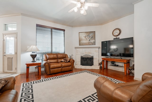 living room featuring a stone fireplace, ornamental molding, and dark hardwood / wood-style flooring