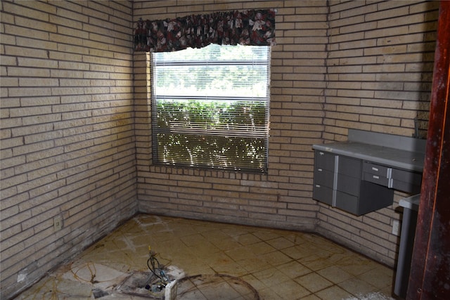 unfurnished dining area featuring tile patterned flooring and brick wall