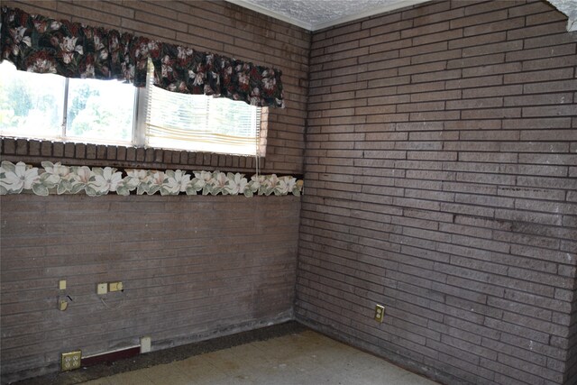 empty room featuring tile patterned floors, a textured ceiling, and brick wall