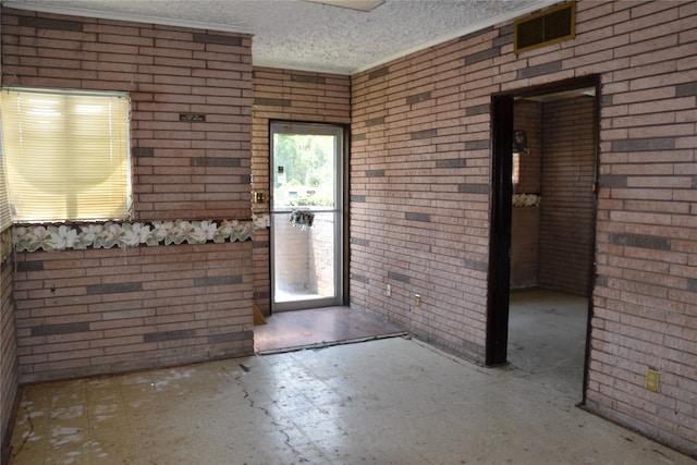 doorway with brick wall and a textured ceiling