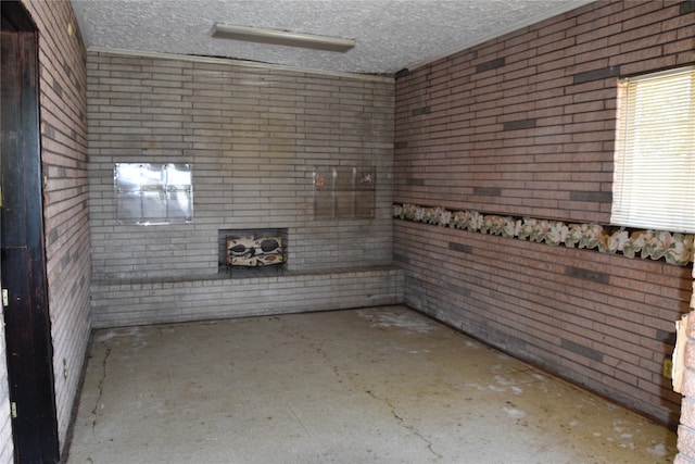 interior space featuring concrete floors, brick wall, and a textured ceiling