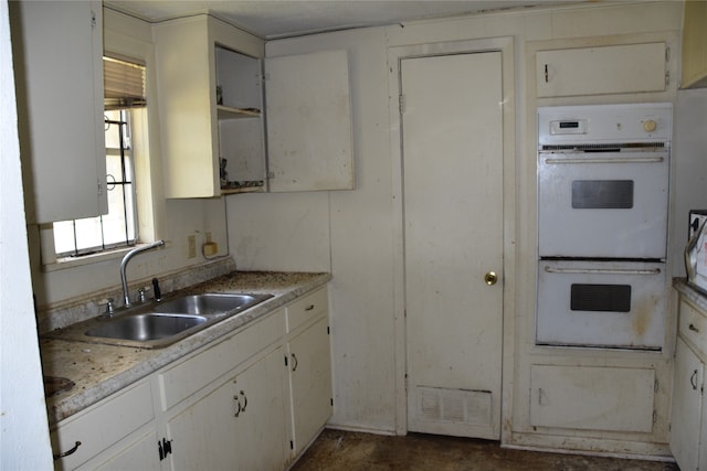 kitchen with sink, white double oven, and white cabinetry