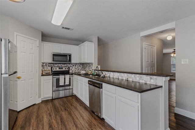 kitchen with kitchen peninsula, sink, white cabinets, and appliances with stainless steel finishes