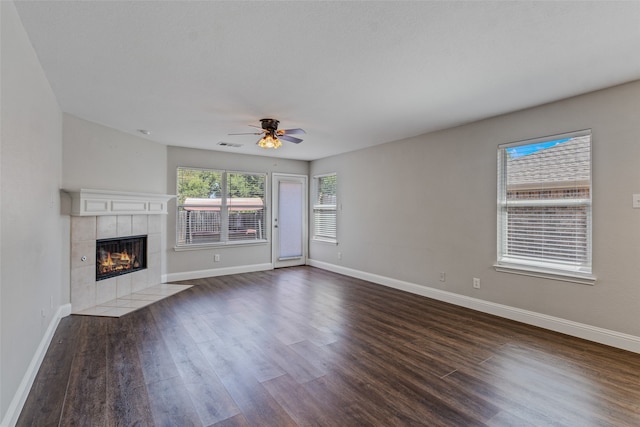 unfurnished living room with a fireplace, ceiling fan, and dark wood-type flooring