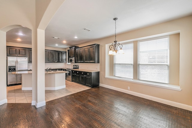 kitchen featuring a kitchen island, appliances with stainless steel finishes, light stone counters, and dark brown cabinetry