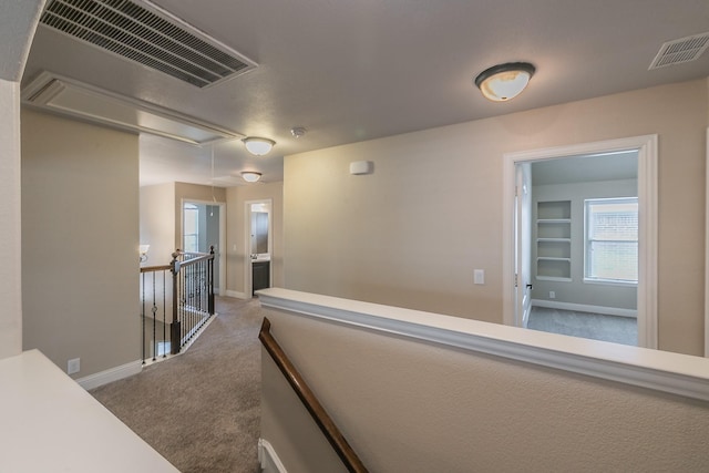 hallway with built in shelves and carpet flooring