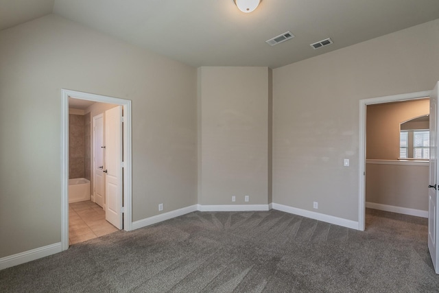 unfurnished bedroom featuring light carpet, lofted ceiling, and ensuite bathroom