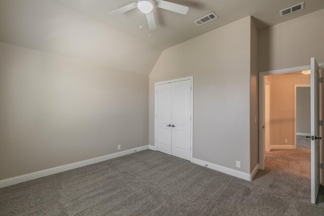 unfurnished bedroom with ceiling fan, lofted ceiling, dark carpet, and a closet