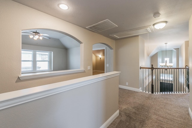 hall featuring lofted ceiling, a notable chandelier, and carpet