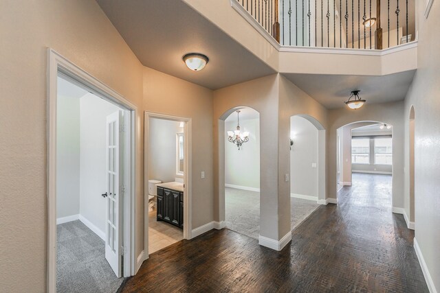 corridor featuring dark wood-type flooring and a chandelier