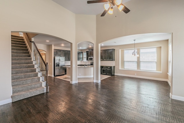 unfurnished living room featuring ceiling fan, dark hardwood / wood-style floors, sink, and a towering ceiling