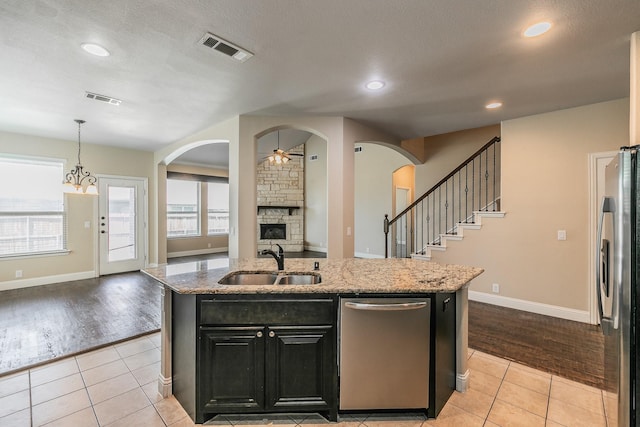 kitchen featuring sink, light tile patterned floors, stainless steel appliances, and a center island with sink