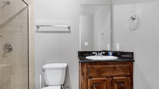 bathroom featuring toilet, a tile shower, and vanity