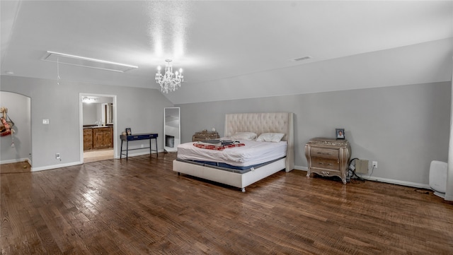 bedroom featuring connected bathroom, an inviting chandelier, and dark hardwood / wood-style floors