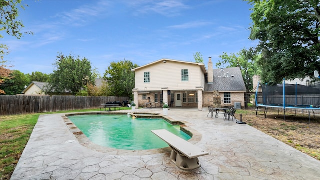 view of pool featuring a trampoline, a diving board, and a patio