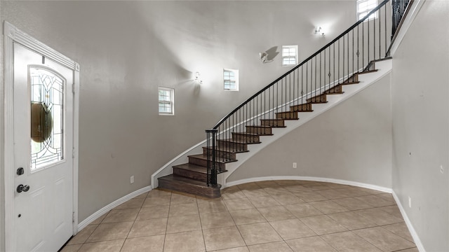 foyer entrance with a high ceiling, a healthy amount of sunlight, and light tile patterned floors