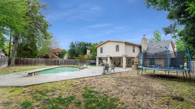 view of swimming pool featuring a trampoline, a diving board, and a patio area