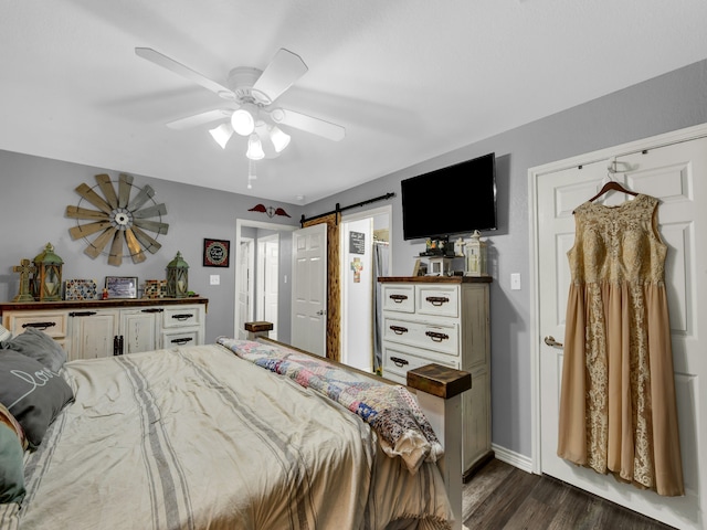 bedroom featuring ceiling fan, dark wood-type flooring, and a barn door