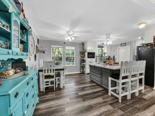 kitchen featuring black appliances, white cabinets, dark hardwood / wood-style flooring, a center island, and ceiling fan