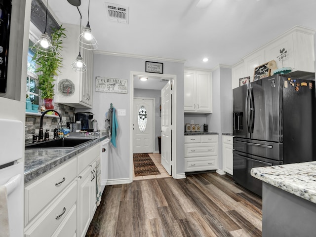 kitchen featuring white cabinetry, tasteful backsplash, sink, black fridge, and dark wood-type flooring