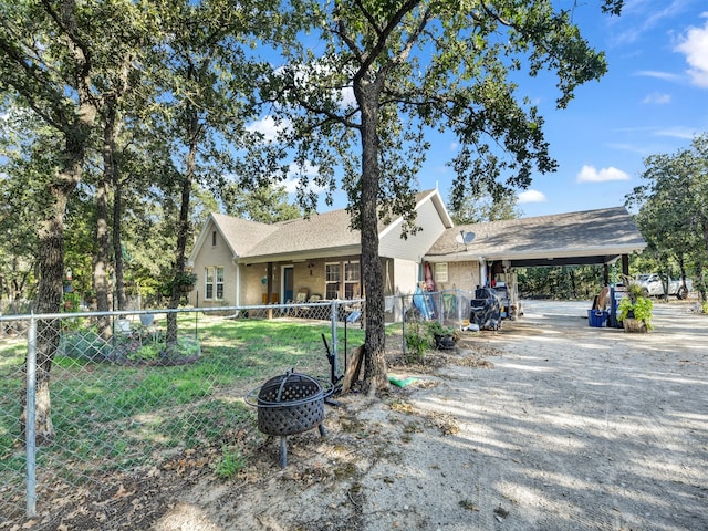 ranch-style home featuring a carport and an outdoor fire pit