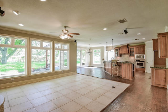 kitchen with appliances with stainless steel finishes, premium range hood, tasteful backsplash, a breakfast bar, and light tile patterned flooring