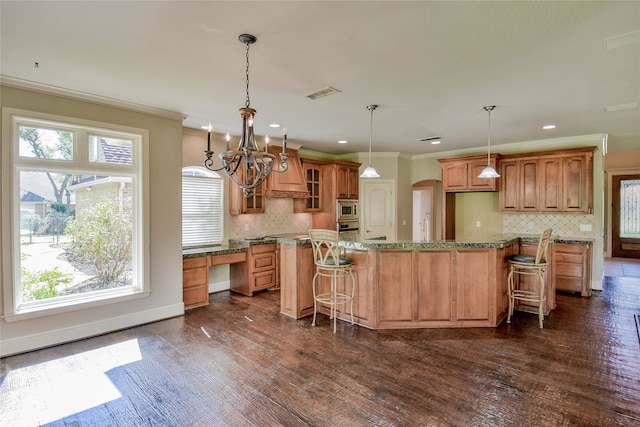 kitchen featuring backsplash, dark wood-type flooring, a chandelier, appliances with stainless steel finishes, and a center island